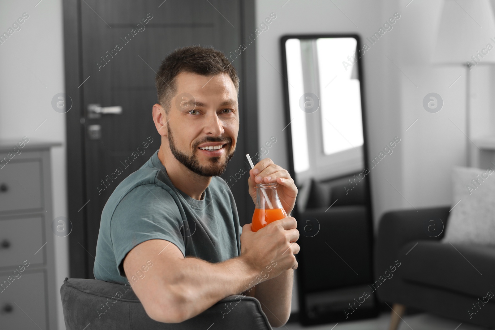 Photo of Man holding bottle of delicious juice at home, space for text