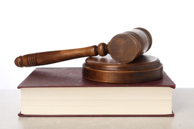 Photo of Wooden gavel, sound block and book on light table against white background