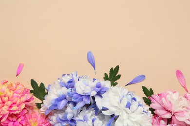 Photo of Beautiful chrysanthemums with leaves on beige background, flat lay. Space for text