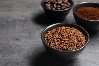 Bowls of beans, instant and ground coffee on grey table, closeup. Space for text