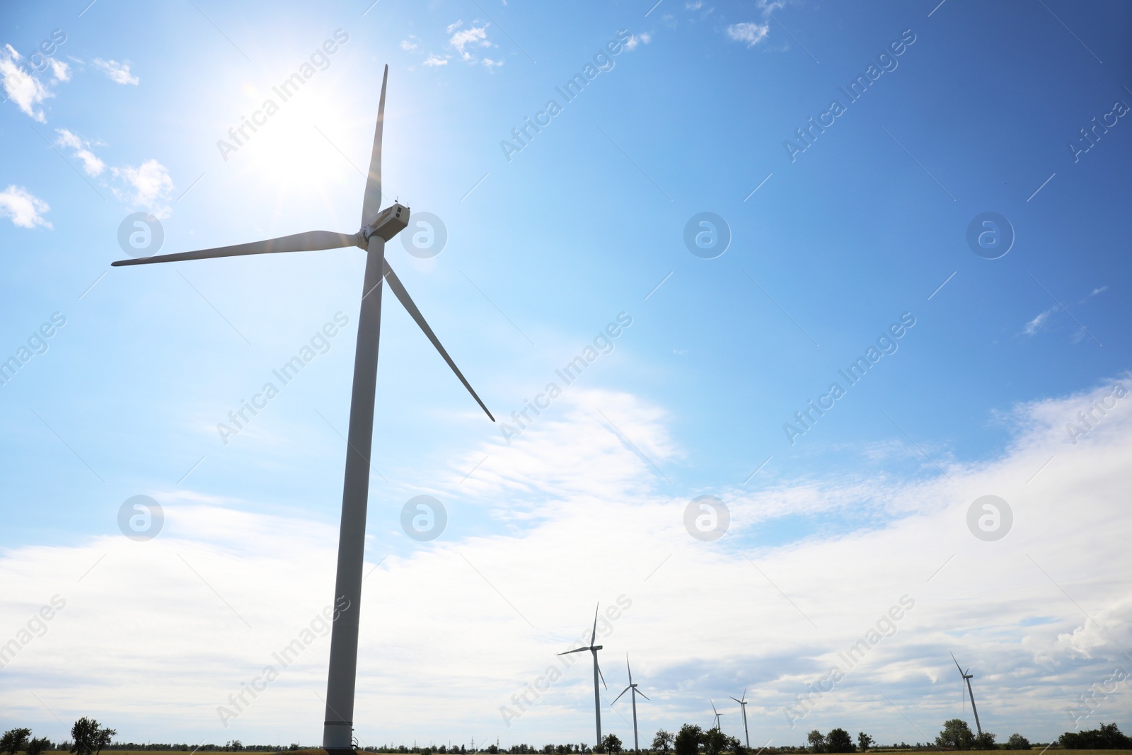 Photo of Field with wind turbines, low angle view. Alternative energy source