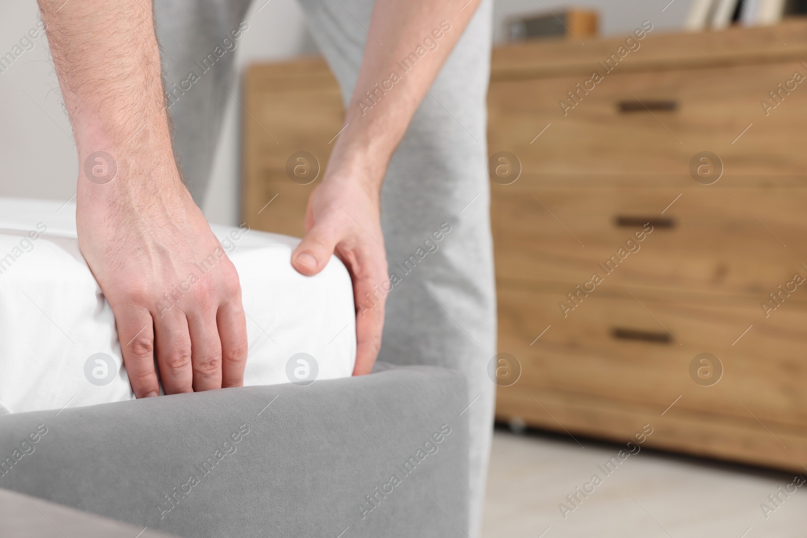 Photo of Man changing bed linens at home, closeup. Space for text