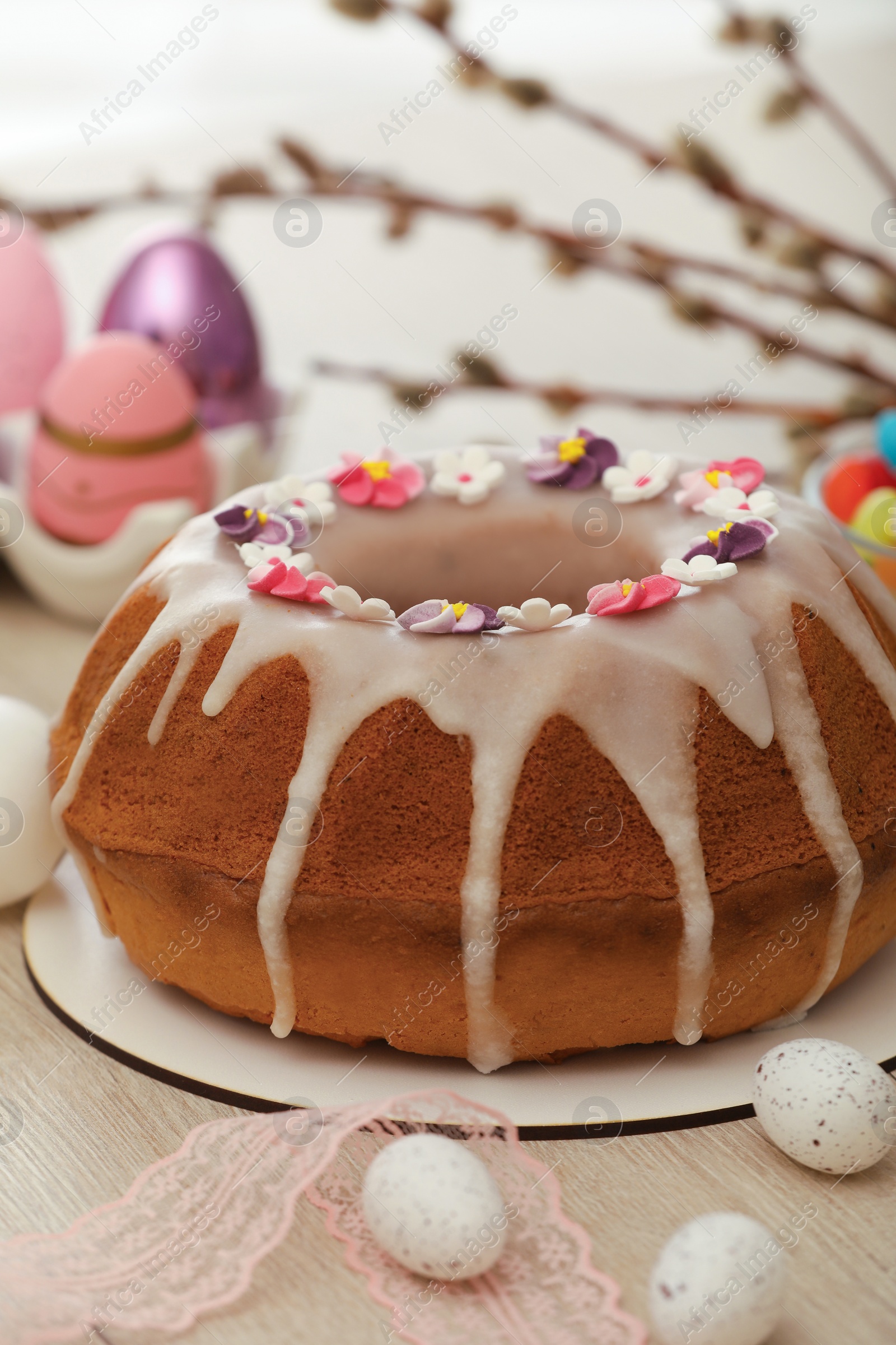 Photo of Delicious Easter cake decorated with sprinkles near painted eggs on white wooden table