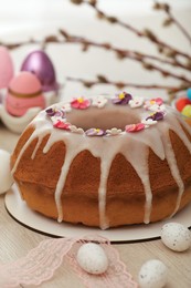 Photo of Delicious Easter cake decorated with sprinkles near painted eggs on white wooden table