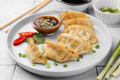 Photo of Delicious gyoza (asian dumplings) with green onions and soy sauce on table, closeup