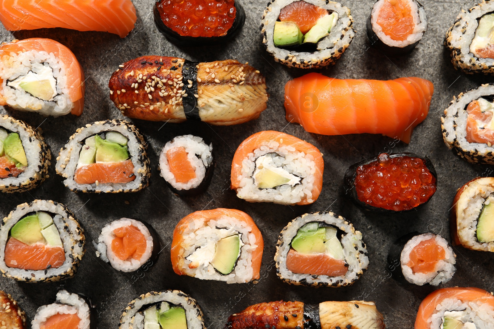 Photo of Different tasty sushi rolls on grey table, flat lay