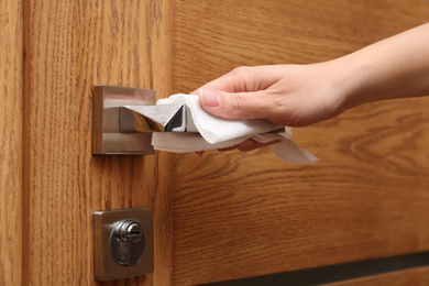 Photo of Woman using napkin to open door indoors, closeup