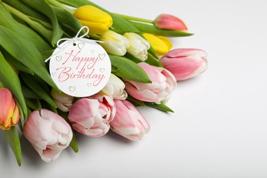 Beautiful bouquet of tulip flowers with Happy Birthday card on white background
