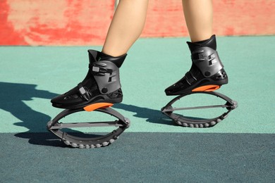 Woman with kangoo jumping boots in workout park, closeup
