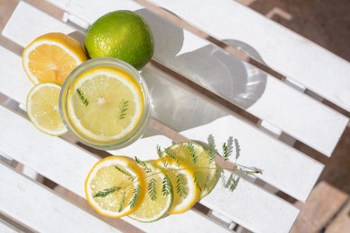Photo of Delicious refreshing lemonade and slices of citrus on white wooden table outdoors, flat lay. Space for text