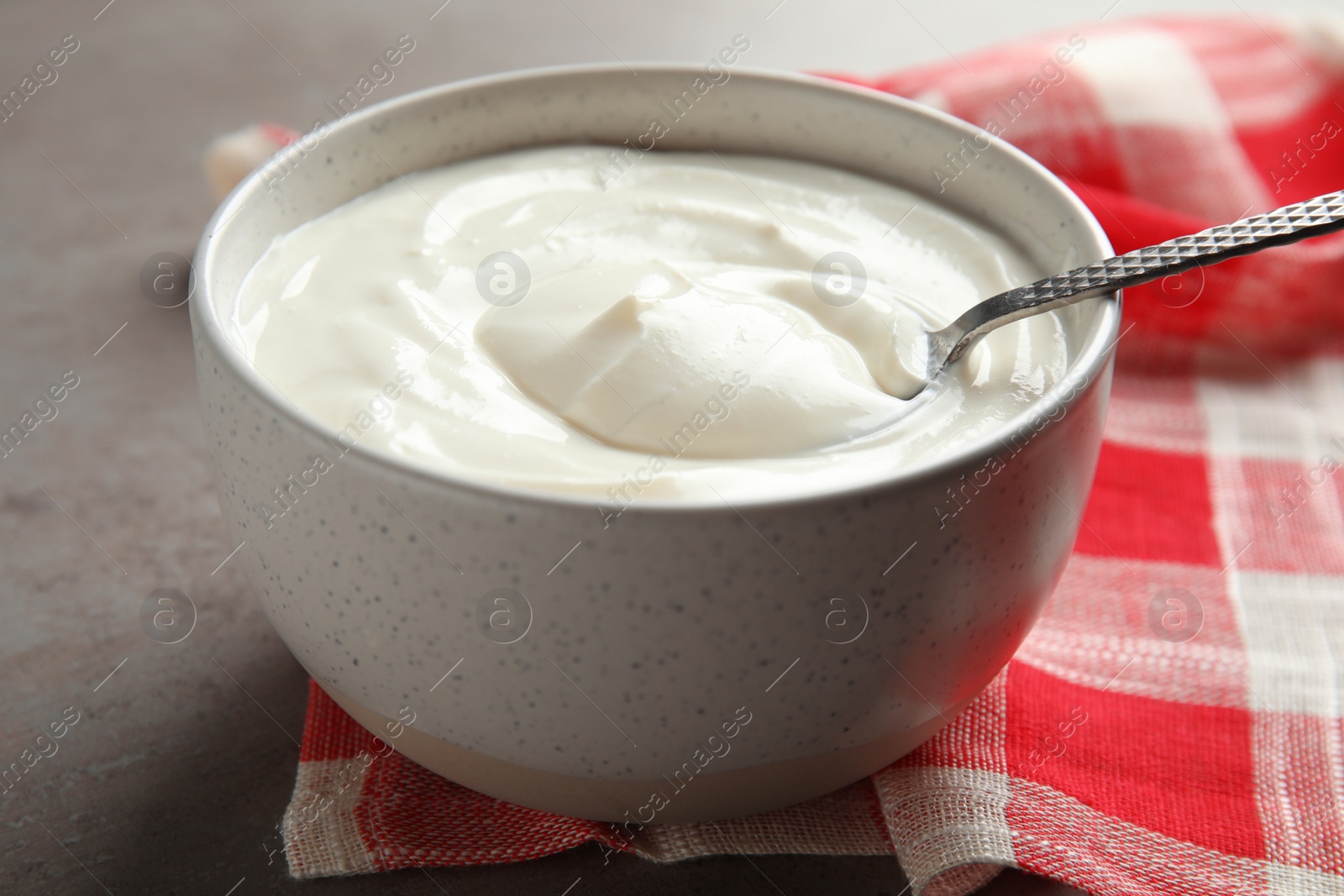 Photo of Bowl with fresh yogurt and spoon on table