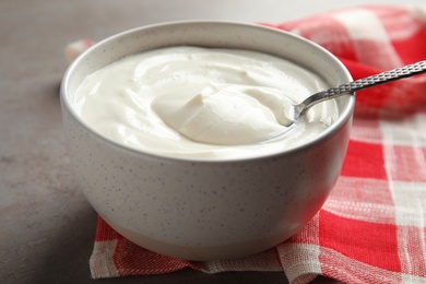 Photo of Bowl with fresh yogurt and spoon on table