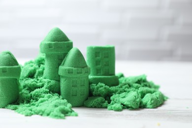 Photo of Castle figures made of green kinetic sand on white table, closeup