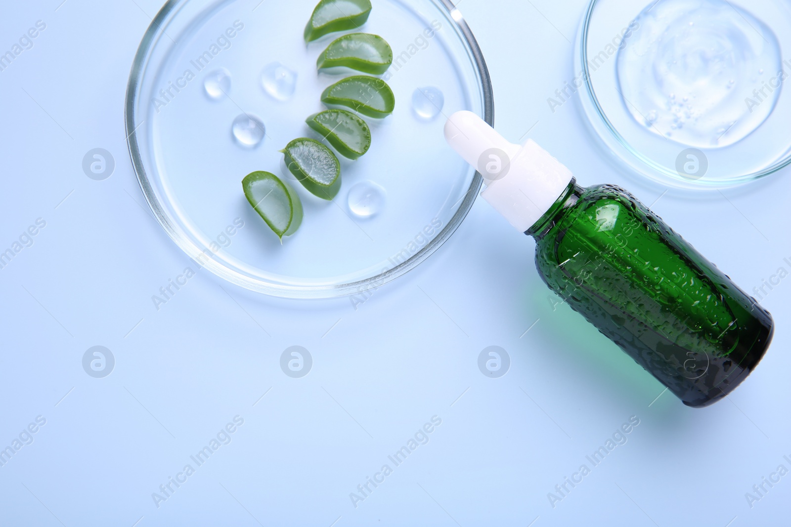 Photo of Cut aloe vera, bottle and cosmetic gel on light blue background, flat lay. Space for text