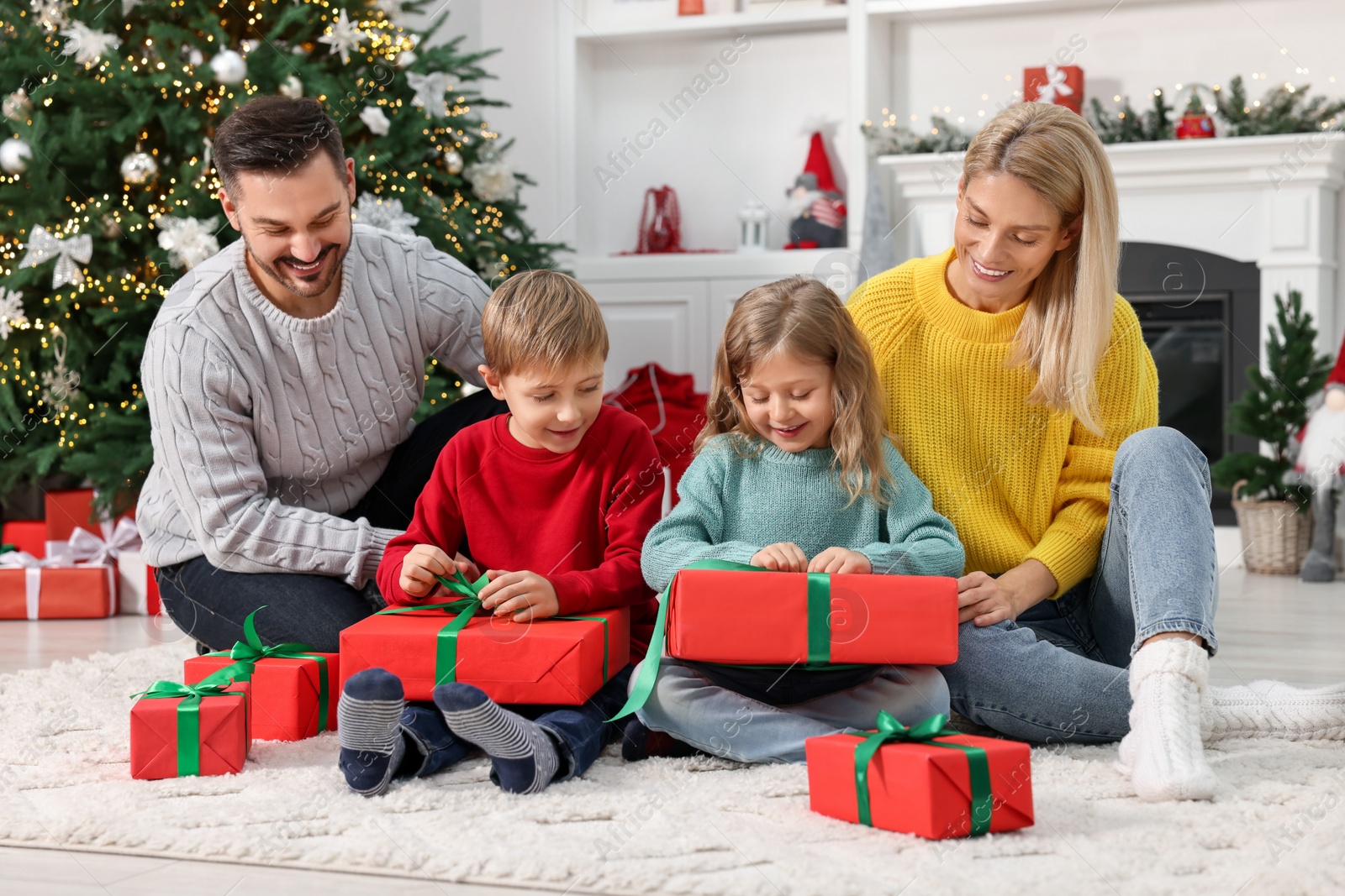 Photo of Parents and their children opening Christmas gifts at home