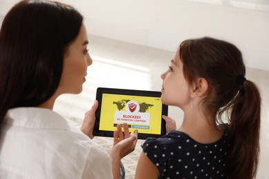 Photo of Mother using parental control app on tablet to ensure her child's safety at home