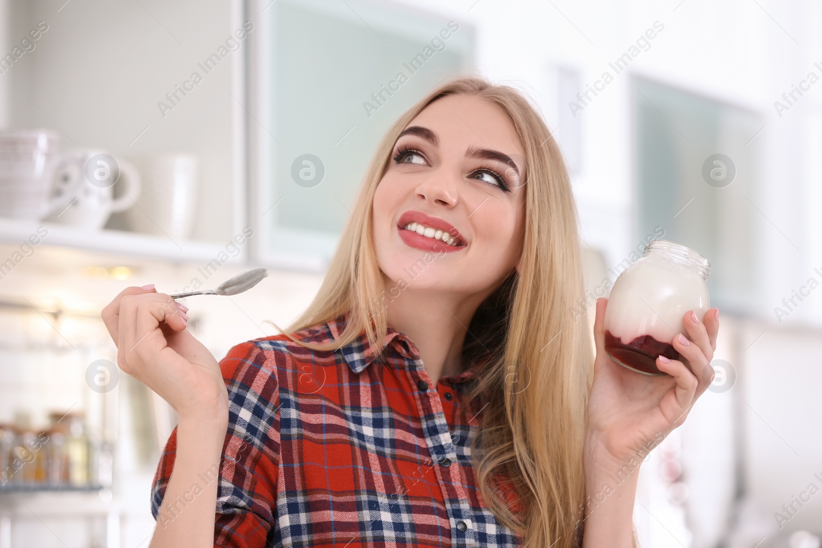 Photo of Young woman with yogurt in kitchen