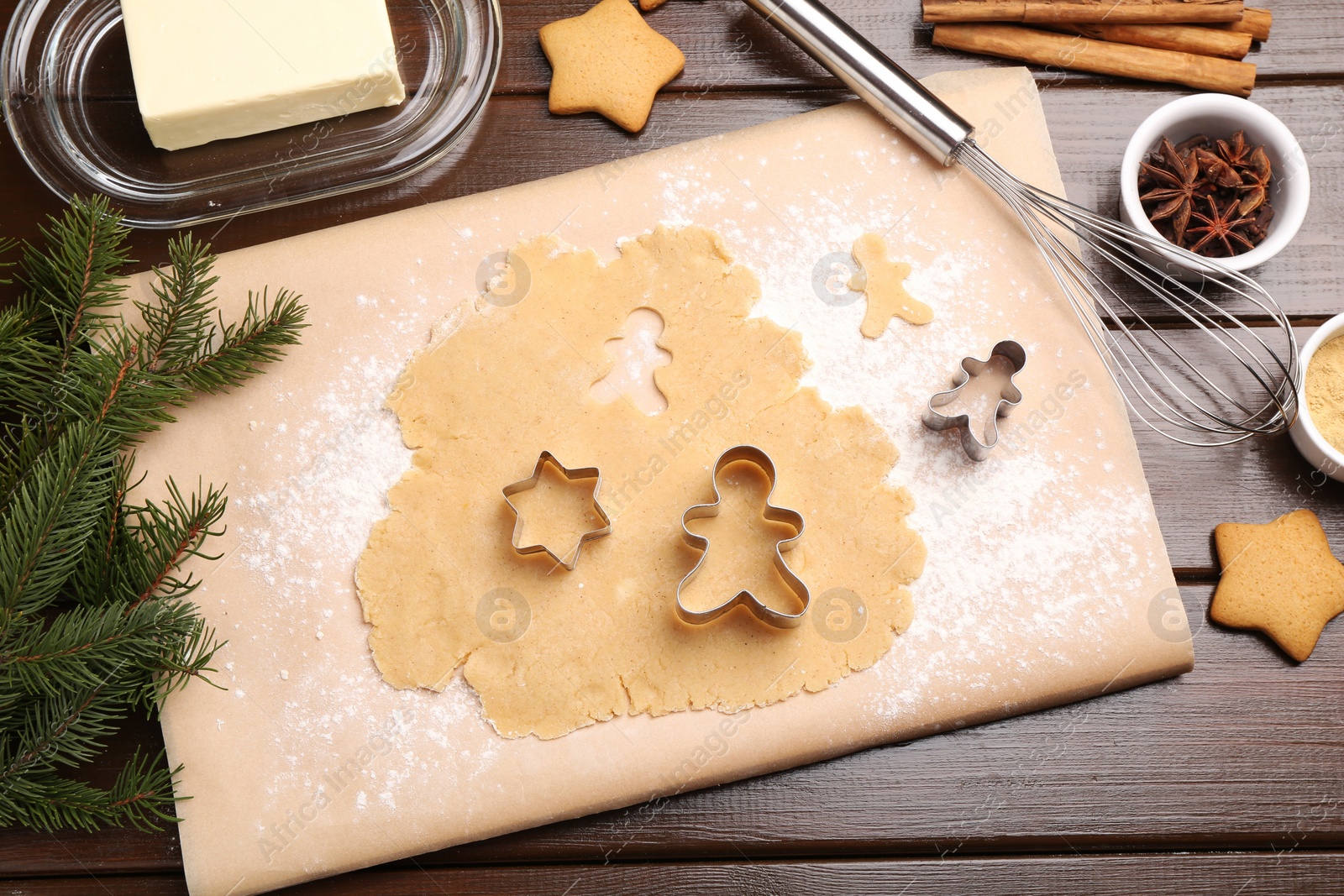 Photo of Making Christmas cookies. Flat lay composition with cutters and raw dough on wooden table