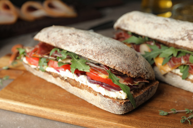 Delicious sandwiches with fresh vegetables and prosciutto on table, closeup