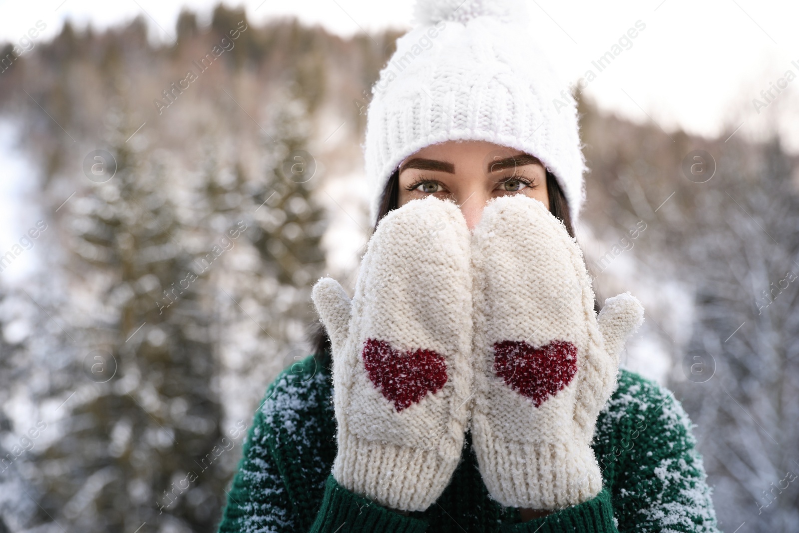 Photo of Beautiful young woman wearing knitted mittens on winter day