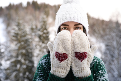 Beautiful young woman wearing knitted mittens on winter day