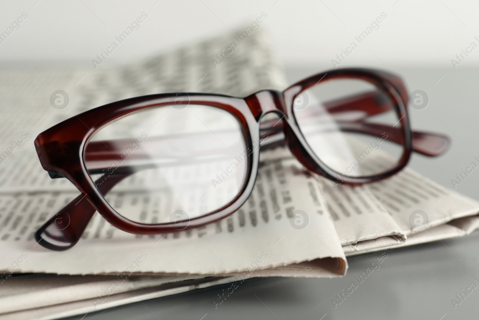 Photo of Newspapers and glasses on grey table, closeup