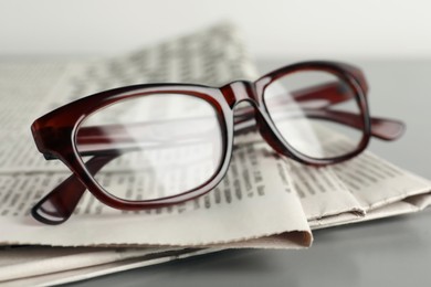 Photo of Newspapers and glasses on grey table, closeup