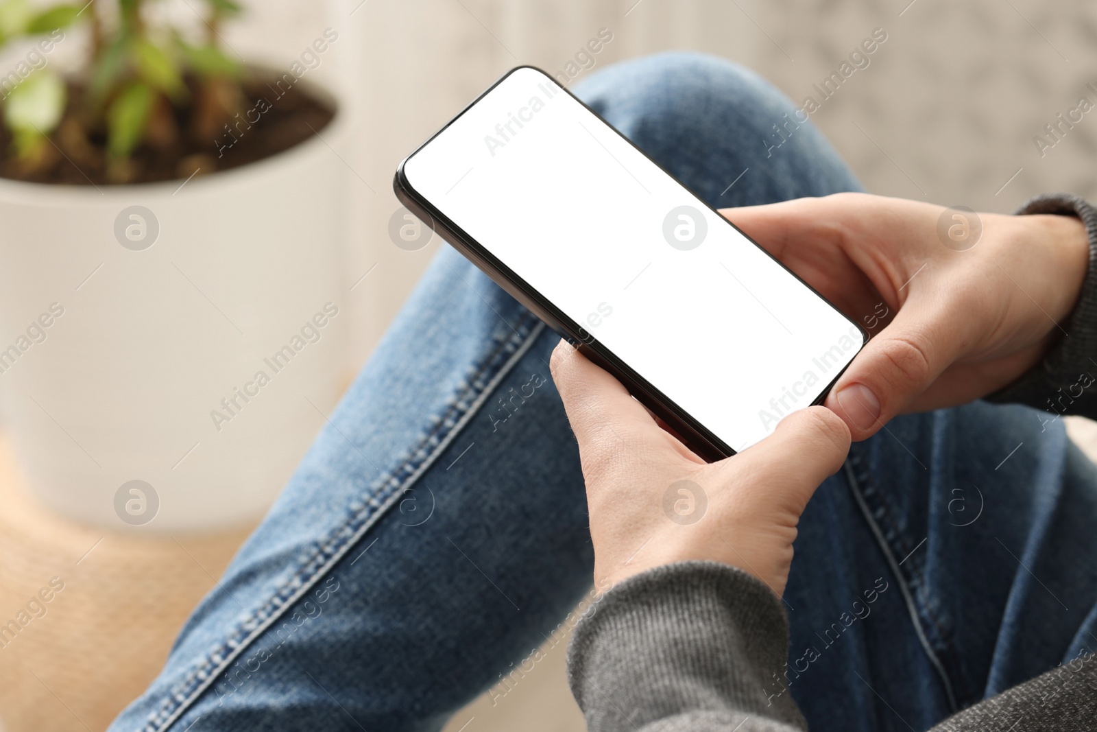 Photo of Man using smartphone with blank screen indoors, closeup. Mockup for design