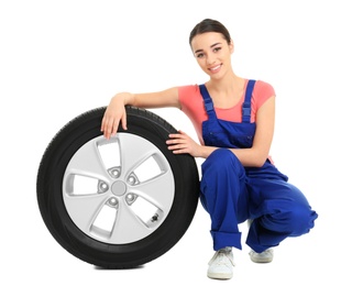Photo of Female mechanic in uniform with car tire on white background