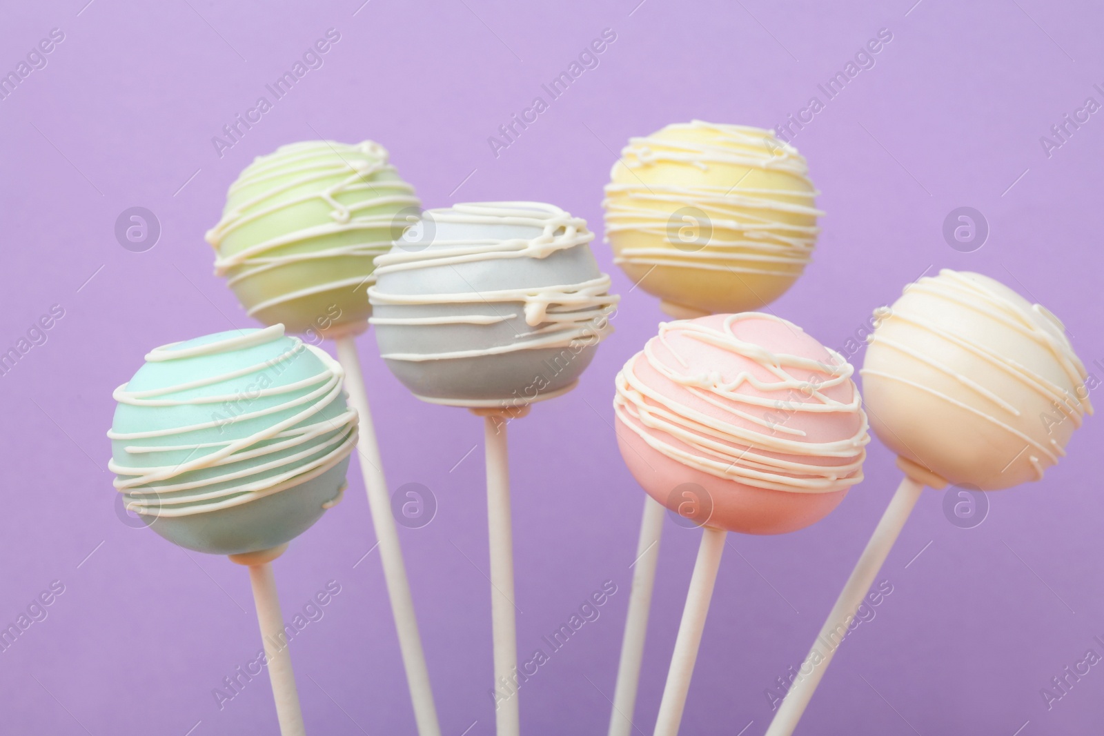 Photo of Sweet colorful cake pops on purple background