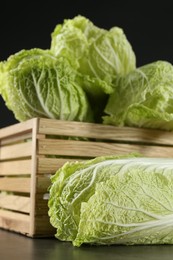 Fresh ripe Chinese cabbages and wooden crate on grey table