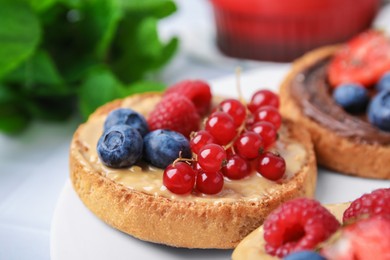 Photo of Tasty organic rusks with different toppings served on white table, closeup