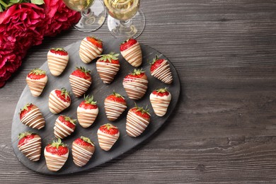 Delicious chocolate covered strawberries, sparkling wine and flowers on wooden table, flat lay. Space for text