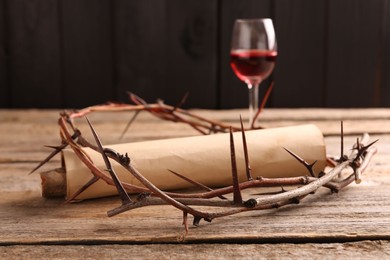 Photo of Crown of thorns, old scroll and glass with wine on wooden table, selective focus