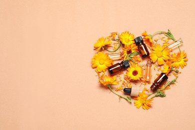 Heart made of bottles with essential oils and beautiful calendula flowers on beige background, flat lay. Space for text