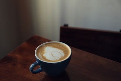 Cup of aromatic coffee on wooden table in cafe