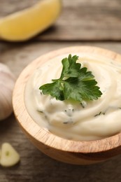 Photo of Tasty sauce with garlic and parsley on wooden table, closeup