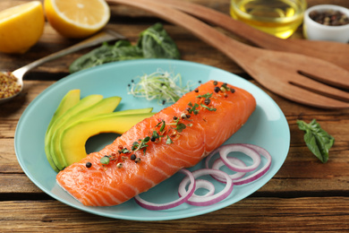 Photo of Delicious fresh salmon with spinach, avocado and onion served on wooden table