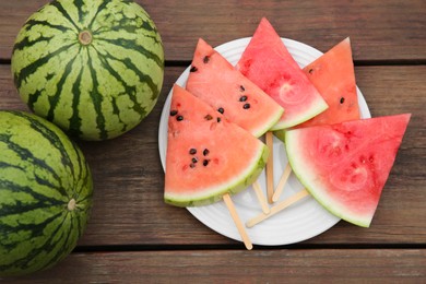 Whole and sliced delicious ripe watermelons on wooden table, flat lay