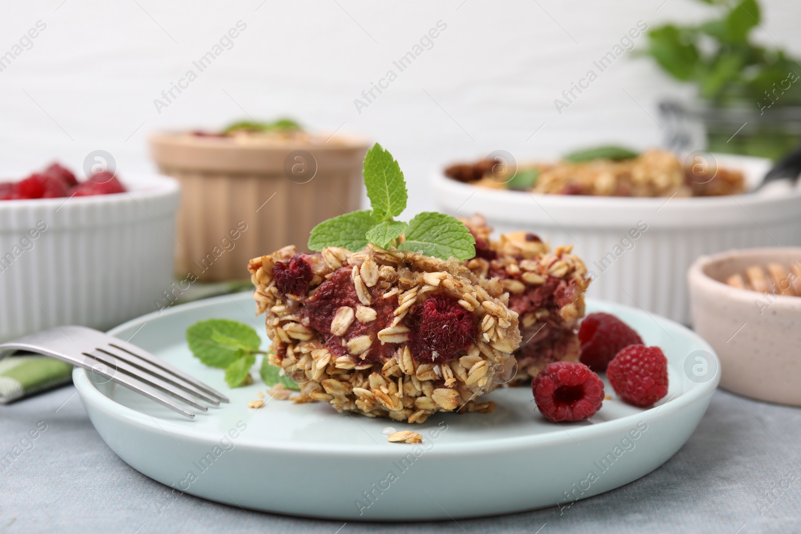 Photo of Tasty baked oatmeal with raspberries on light grey table, closeup