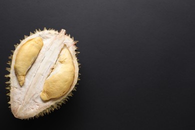Photo of Fresh ripe durian on black background, top view. Space for text