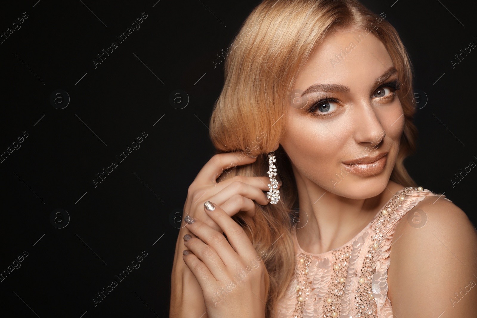 Photo of Beautiful young woman with elegant jewelry on dark background. Space for text