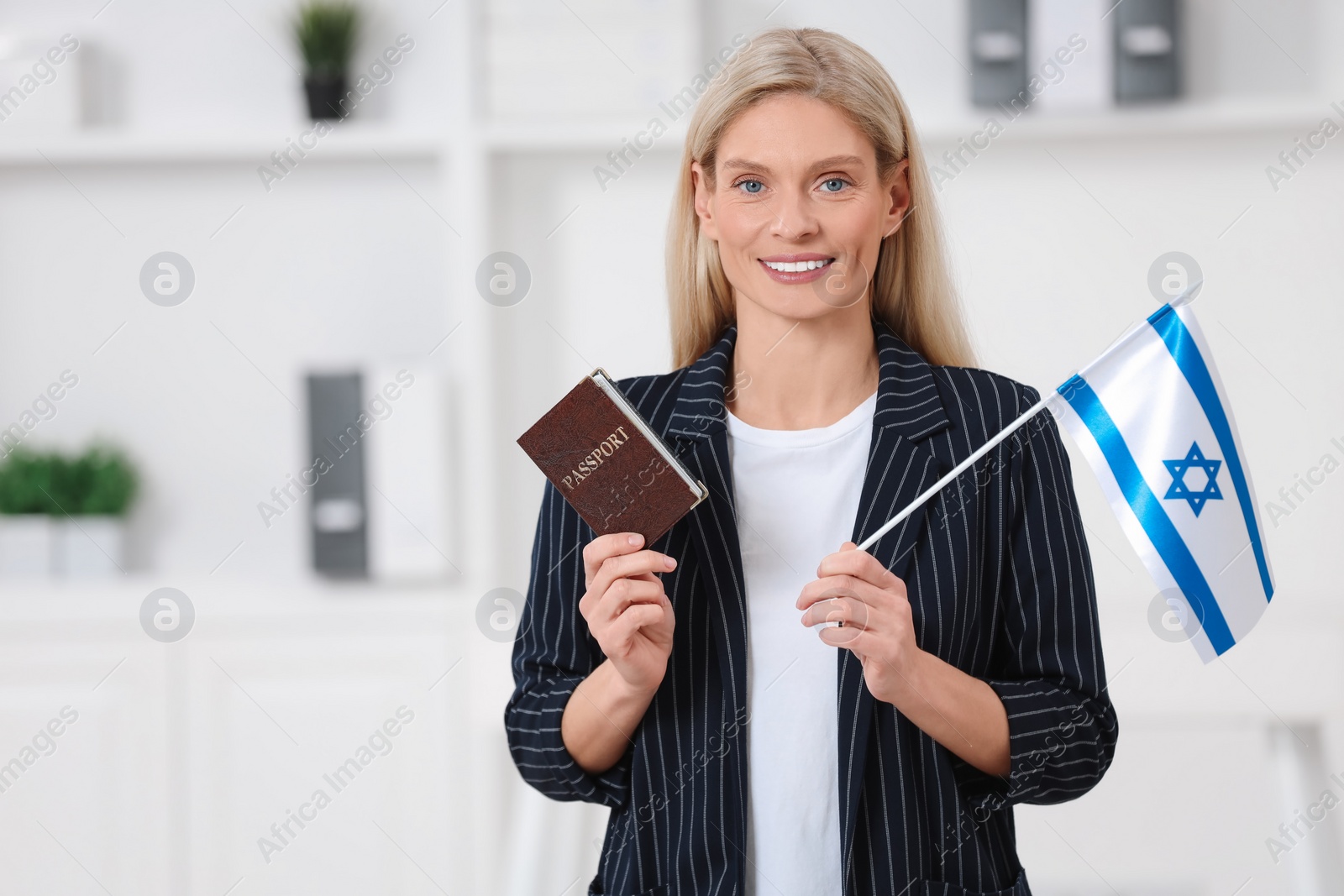 Photo of Immigration. Happy woman with passport and flag of Israel indoors, space for text