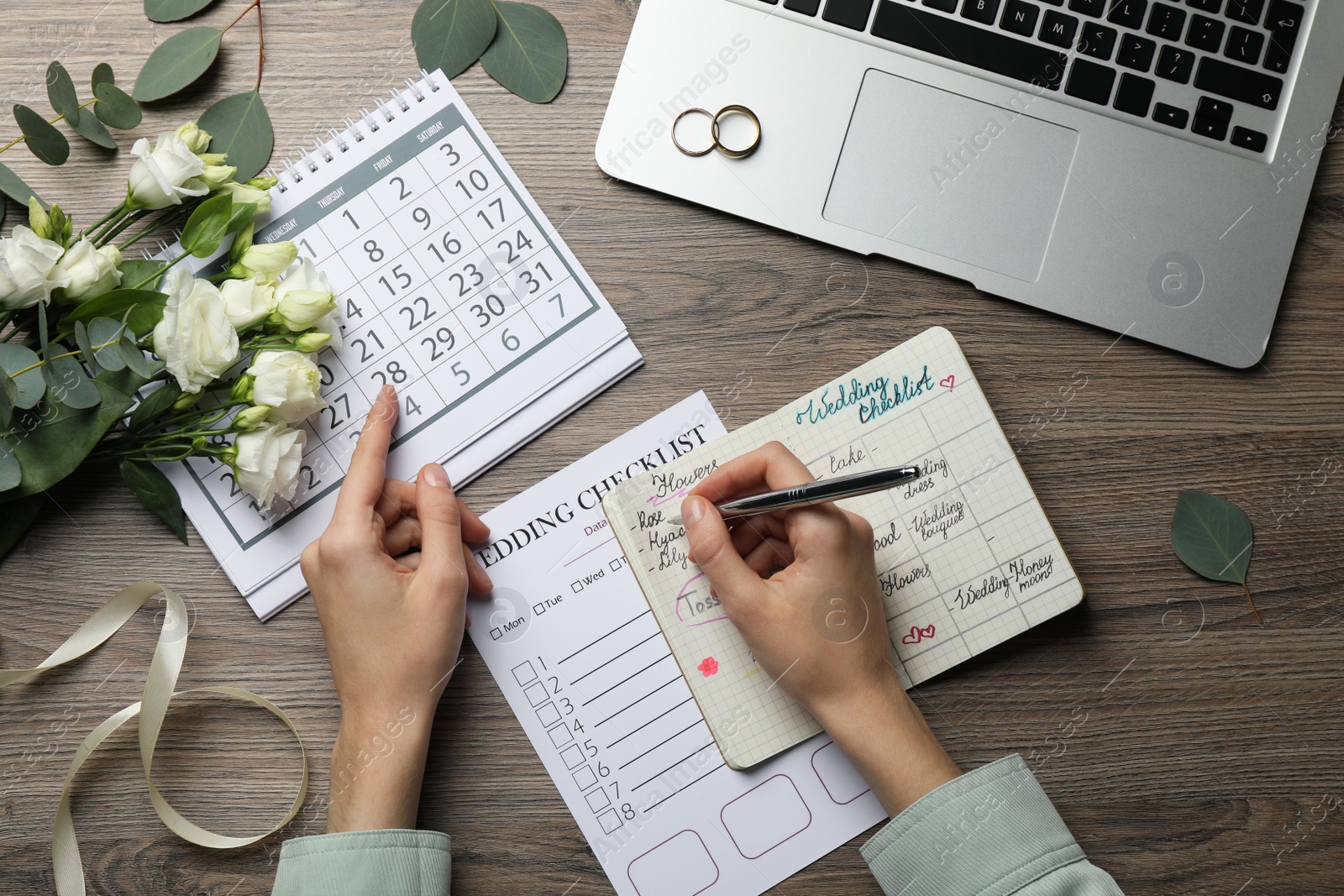 Photo of Woman filling Wedding Checklist in planner at wooden table, top view