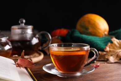 Photo of Cup of hot drink on wooden table against black background. Cozy autumn atmosphere