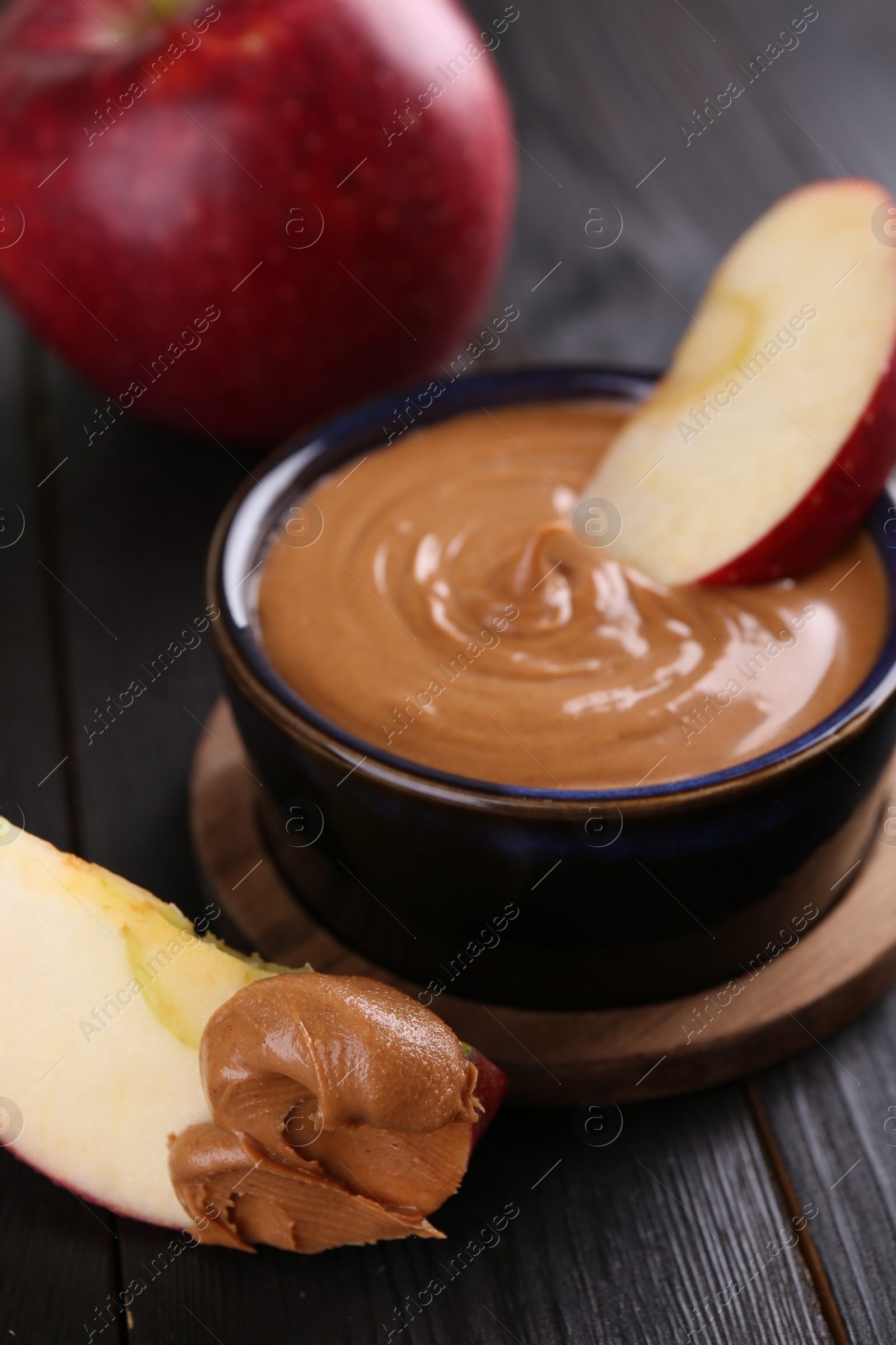 Photo of Slices of fresh apple with peanut butter on wooden table, closeup
