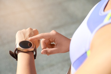 Photo of Woman checking fitness tracker after training outdoors, closeup