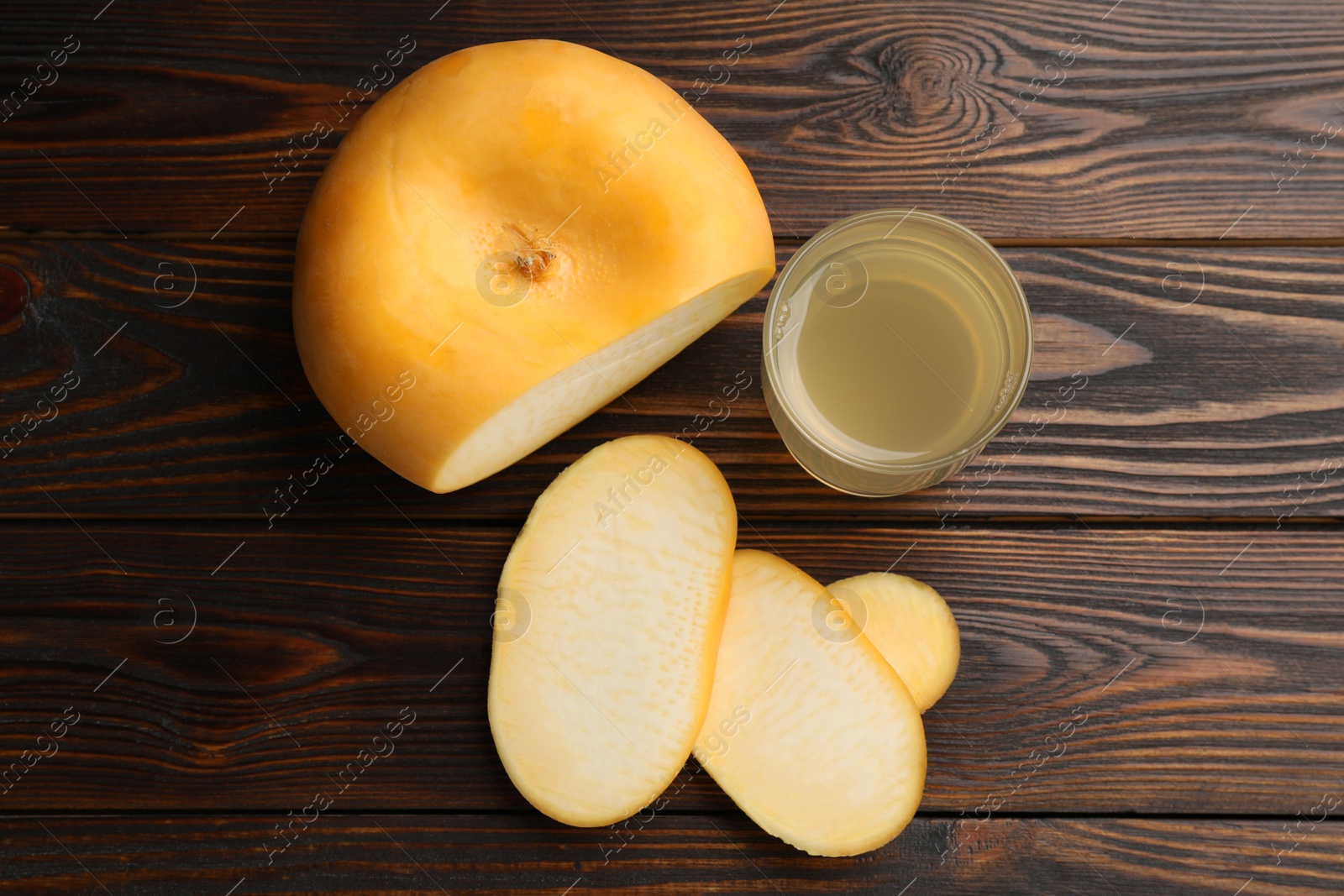 Photo of Glass of fresh natural turnip juice and cut root on wooden table, flat lay