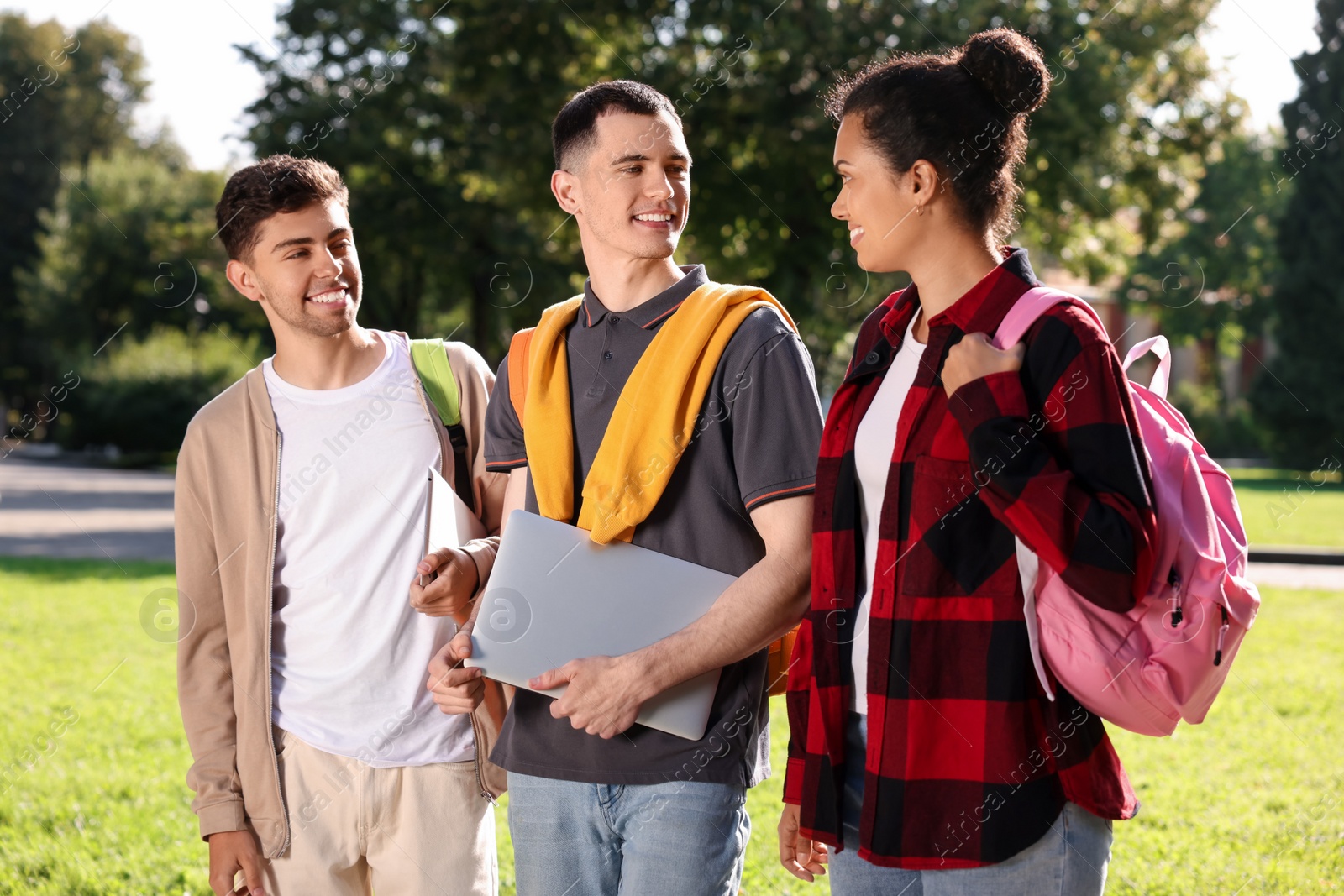 Photo of Happy young students spending time together in park