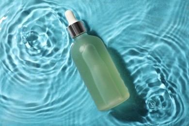 Bottle of hydrophilic oil in water on light blue background, top view